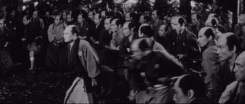 Movie still from “Sanjuro” (1962), directed by Akira Kurosawa – A large group of people sitting in front of trees; Wide shot, High angle
