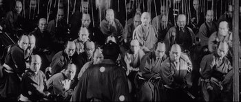 Movie still from “Sanjuro” (1962), directed by Akira Kurosawa – A group of men sitting in front of each other; Wide shot, High angle