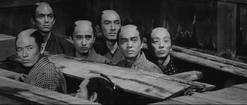 Movie still from “Sanjuro” (1962), directed by Akira Kurosawa – A black and white photo of a group of people with their heads cut out; Medium shot, High angle
