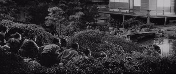Movie still from “Sanjuro” (1962), directed by Akira Kurosawa – A black and white photo of people sitting in a garden; Extreme Wide shot, High angle