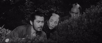 Movie still from “Sanjuro” (1962), directed by Akira Kurosawa – A group of men standing next to each other in bushes; Medium shot, High angle