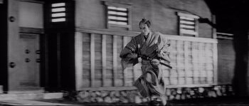 Movie still from “Sanjuro” (1962), directed by Akira Kurosawa – A man in a kimono is running through the street; Wide shot, Low angle