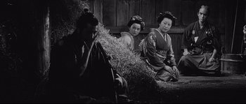 Movie still from “Sanjuro” (1962), directed by Akira Kurosawa – A group of people sitting next to each other in front of a pile of hay; Medium shot, Low angle