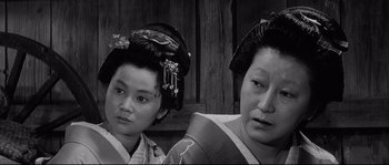 Movie still from “Sanjuro” (1962), directed by Akira Kurosawa – Two geishas in traditional garb , one of which is wearing an elaborate hairdo; Close Up shot, Low angle