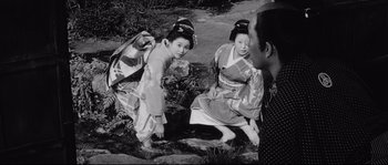 Movie still from “Sanjuro” (1962), directed by Akira Kurosawa – Two geishas are sitting on the ground and one of them is kneeling down; Medium shot, High angle
