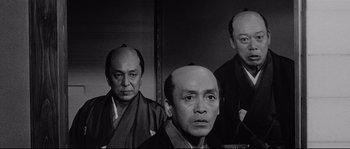 Movie still from “Sanjuro” (1962), directed by Akira Kurosawa – A group of three men standing next to each other; Close Up shot, Low angle