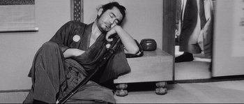 Movie still from “Sanjuro” (1962), directed by Akira Kurosawa – A man is sleeping on the floor with a sword; Medium shot, High angle