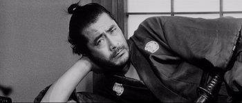 Movie still from “Sanjuro” (1962), directed by Akira Kurosawa – Black and white photograph of a man with a cat pin on his jacket; Close Up shot, Low angle