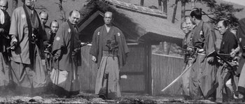 Movie still from “Sanjuro” (1962), directed by Akira Kurosawa – Two men standing in front of a hut in the woods; Wide shot, Low angle