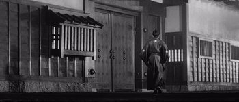 Movie still from “Sanjuro” (1962), directed by Akira Kurosawa – A man in a kimono walking down the street; Wide shot, Low angle