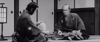 Movie still from “Sanjuro” (1962), directed by Akira Kurosawa – Two men sitting at a table in front of each other; Medium shot, Over the shoulder angle