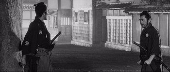 Movie still from “Sanjuro” (1962), directed by Akira Kurosawa – A person holding a guitar in a field; Medium shot, Low angle