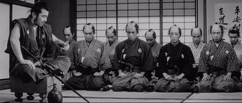 Movie still from “Sanjuro” (1962), directed by Akira Kurosawa – A black and white photo of a group of men sitting on the ground; Medium shot, High angle