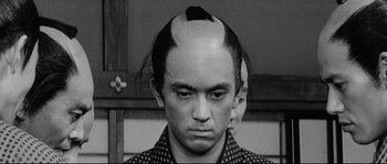 Movie still from “Sanjuro” (1962), directed by Akira Kurosawa – A man with an upside - down hair style on top of his head; Close Up shot, High angle