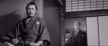 Movie still from “Sanjuro” (1962), directed by Akira Kurosawa – Two men in traditional japanese garb looking at each other in front of an open window; Medium shot, Low angle