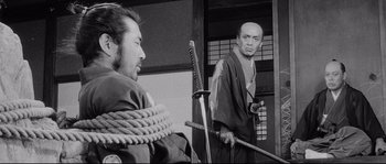 Movie still from “Sanjuro” (1962), directed by Akira Kurosawa – Two men in traditional japanese garb with swords; Medium shot, Over the shoulder angle