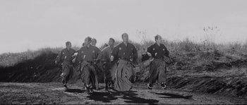 Movie still from “Sanjuro” (1962), directed by Akira Kurosawa – A black and white photo of a group of men in traditional japanese garb; Wide shot, Low angle