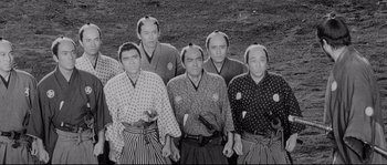 Movie still from “Sanjuro” (1962), directed by Akira Kurosawa – A black and white photo of a group of men in traditional garb; Medium shot, High angle