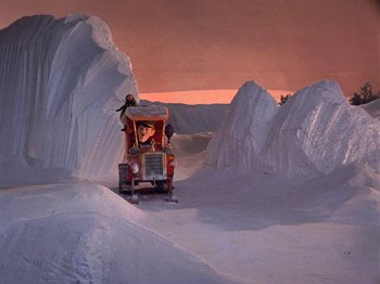 Movie still from “Santa Claus Is Comin' to Town” (1970), directed by Jules Bass – A person riding a snow vehicle on a snowy slope; Extreme Wide shot, High angle