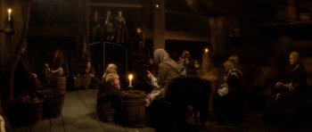 Movie still from “Santa Claus” (1985), directed by Jeannot Szwarc – A group of people sitting around a fire pit; Wide shot, High angle