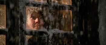 Movie still from “Santa Claus” (1985), directed by Jeannot Szwarc – A woman looking out a window with snow on it; Extreme Close Up shot, Low angle