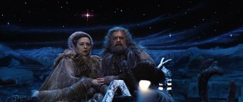 Movie still from “Santa Claus” (1985), directed by Jeannot Szwarc – A man and a woman sitting on a boat in the stars; Medium shot, Low angle
