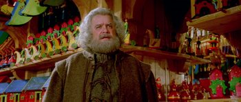 Movie still from “Santa Claus” (1985), directed by Jeannot Szwarc – An old man with a beard and a mustache wearing a cape; Close Up shot, Low angle