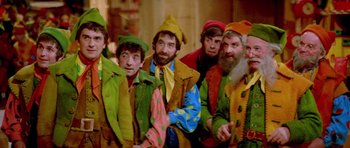 Movie still from “Santa Claus” (1985), directed by Jeannot Szwarc – A group of men dressed in colorful costumes; Medium shot, High angle