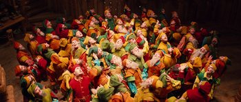 Movie still from “Santa Claus” (1985), directed by Jeannot Szwarc – A large group of people dressed in colorful costumes; Wide shot, Overhead angle