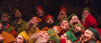 Movie still from “Santa Claus” (1985), directed by Jeannot Szwarc – A group of people dressed as dwarfs in the snow; Medium shot, Low angle