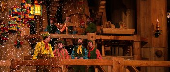 Movie still from “Santa Claus” (1985), directed by Jeannot Szwarc – A group of people dressed in colorful costumes; Wide shot, High angle