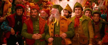 Movie still from “Santa Claus” (1985), directed by Jeannot Szwarc – A group of men dressed as elves standing next to each other; Medium shot, Low angle