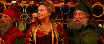 Movie still from “Santa Claus” (1985), directed by Jeannot Szwarc – A woman in a colorful dress is looking up; Medium shot, Over the shoulder angle