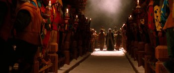 Movie still from “Santa Claus” (1985), directed by Jeannot Szwarc – A group of people standing in a room with candles; Extreme Wide shot, High angle