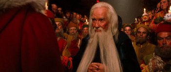 Movie still from “Santa Claus” (1985), directed by Jeannot Szwarc – A group of people dressed up in costumes and wigs; Close Up shot, Over the shoulder angle