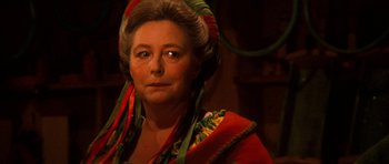 Movie still from “Santa Claus” (1985), directed by Jeannot Szwarc – An older woman wearing a red and green dress; Close Up shot, Over the shoulder angle
