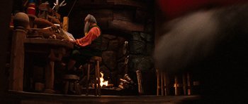 Movie still from “Santa Claus” (1985), directed by Jeannot Szwarc – A man sitting in front of a fire place; Wide shot, Over the shoulder angle