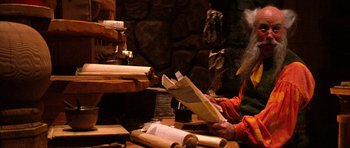 Movie still from “Santa Claus” (1985), directed by Jeannot Szwarc – A person sitting at a table reading a book; Medium shot, High angle