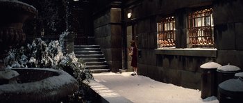 Movie still from “Santa Claus” (1985), directed by Jeannot Szwarc – A woman standing in a snowy alleyway next to a building; Wide shot, High angle