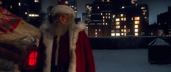 Movie still from “Santa Claus” (1985), directed by Jeannot Szwarc – A man dressed up as santa claus standing in front of a building; Medium shot, Over the shoulder angle