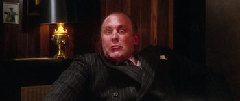 Movie still from “Santa Claus” (1985), directed by Jeannot Szwarc – A man wearing a suit and tie sitting in a chair; Close Up shot, Low angle