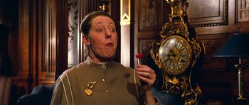 Movie still from “Santa Claus” (1985), directed by Jeannot Szwarc – A woman holding a flower in front of a clock; Close Up shot, Over the shoulder angle
