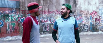 Movie still from “Santa Claus” (1985), directed by Jeannot Szwarc – Two young men are talking in front of a graffiti wall; Medium shot, Over the shoulder angle