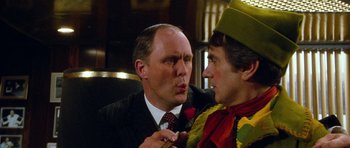 Movie still from “Santa Claus” (1985), directed by Jeannot Szwarc – A man in a suit and a man in a clown costume; Close Up shot, Over the shoulder angle