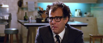 Movie still from “Santa Claus” (1985), directed by Jeannot Szwarc – A person wearing a suit and glasses; Close Up shot, Low angle