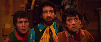 Movie still from “Santa Claus” (1985), directed by Jeannot Szwarc – A man with a beard wearing a colorful shirt and a yellow tie; Medium shot, Low angle