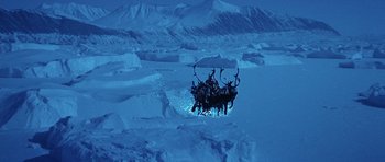 Movie still from “Santa Claus” (1985), directed by Jeannot Szwarc – A group of people riding on the back of a reindeer; Extreme Wide shot, High angle
