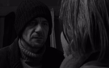 Movie still from “Satantango” (1994), directed by Béla Tarr – A black and white photo of a man and a woman; Close Up shot, Over the shoulder angle