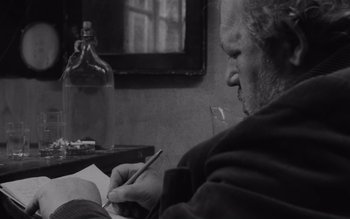 Movie still from “Satantango” (1994), directed by Béla Tarr – An older man writing on a piece of paper; Close Up shot, Over the shoulder angle