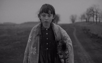 Movie still from “Satantango” (1994), directed by Béla Tarr – A young girl with a cat in her arms; Close Up shot, Over the shoulder angle